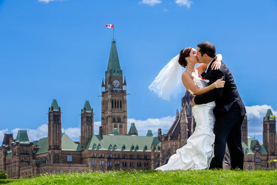 Wedding photography of a recently married couple posing for a portrait with a kiss on Parliament Hill in Ottawa