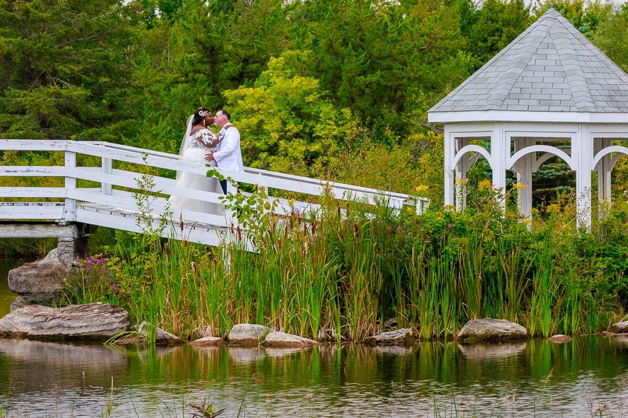 Bride and groom wedding portrait next to a white bridge gazebo at Orchardview.