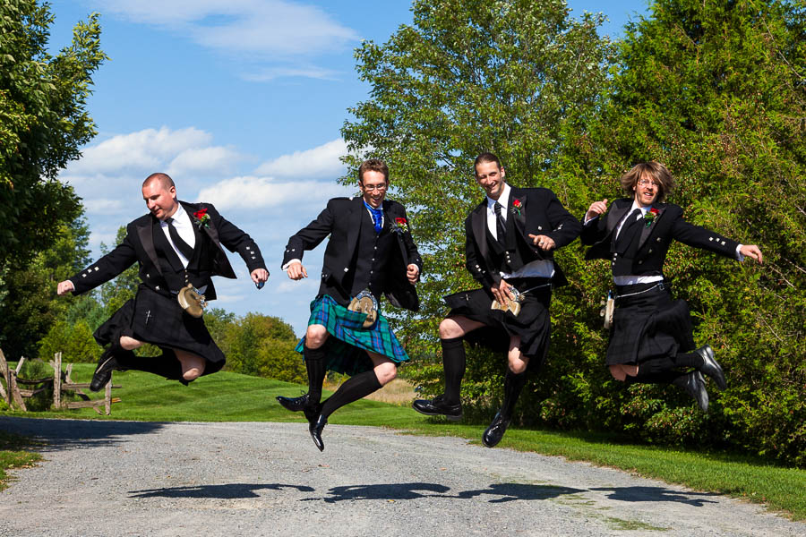 Four groomsmen in Scottish kilts jump for joy at Strathmere.
