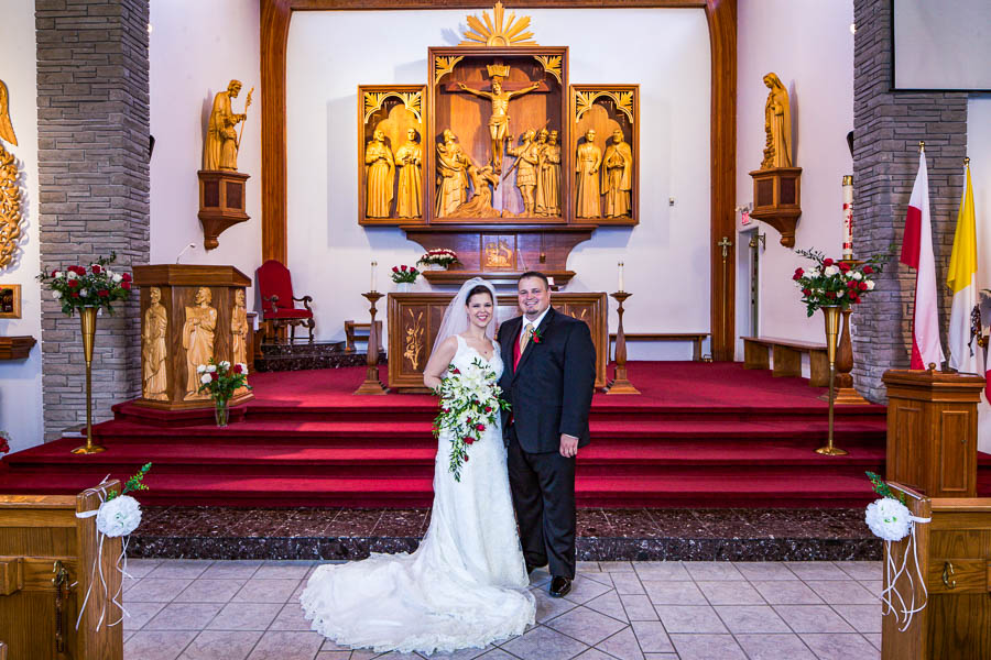 Geneviève and Konrad pose for a wedding portrait at the altar of Saint Hyacinth Roman Catholic Polish Church in Ottawa, Ontario.