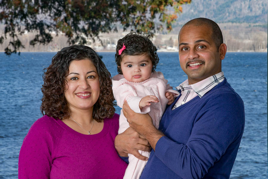 Kamy and Rahan pose with their baby from the comfort of their living room.